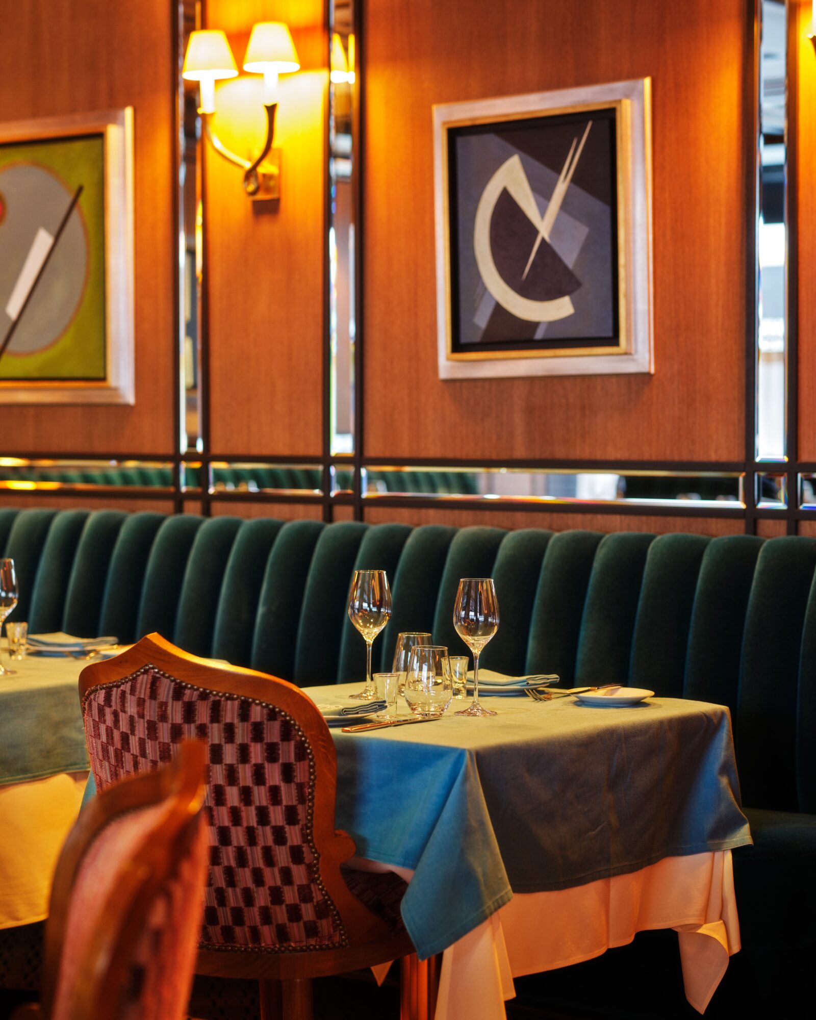 A dining area with a table set for guests, booth seating, and artwork on the walls.