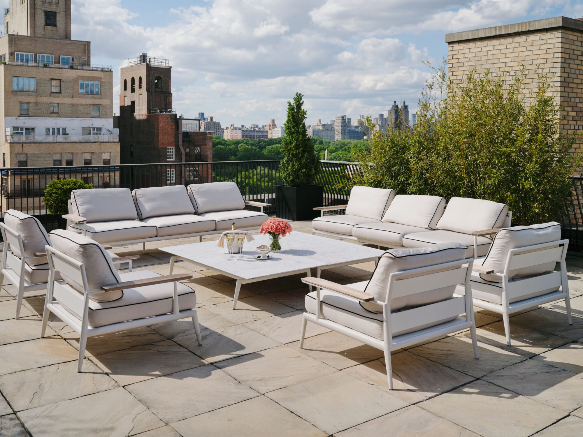 A rooftop patio with white furniture and a city view.